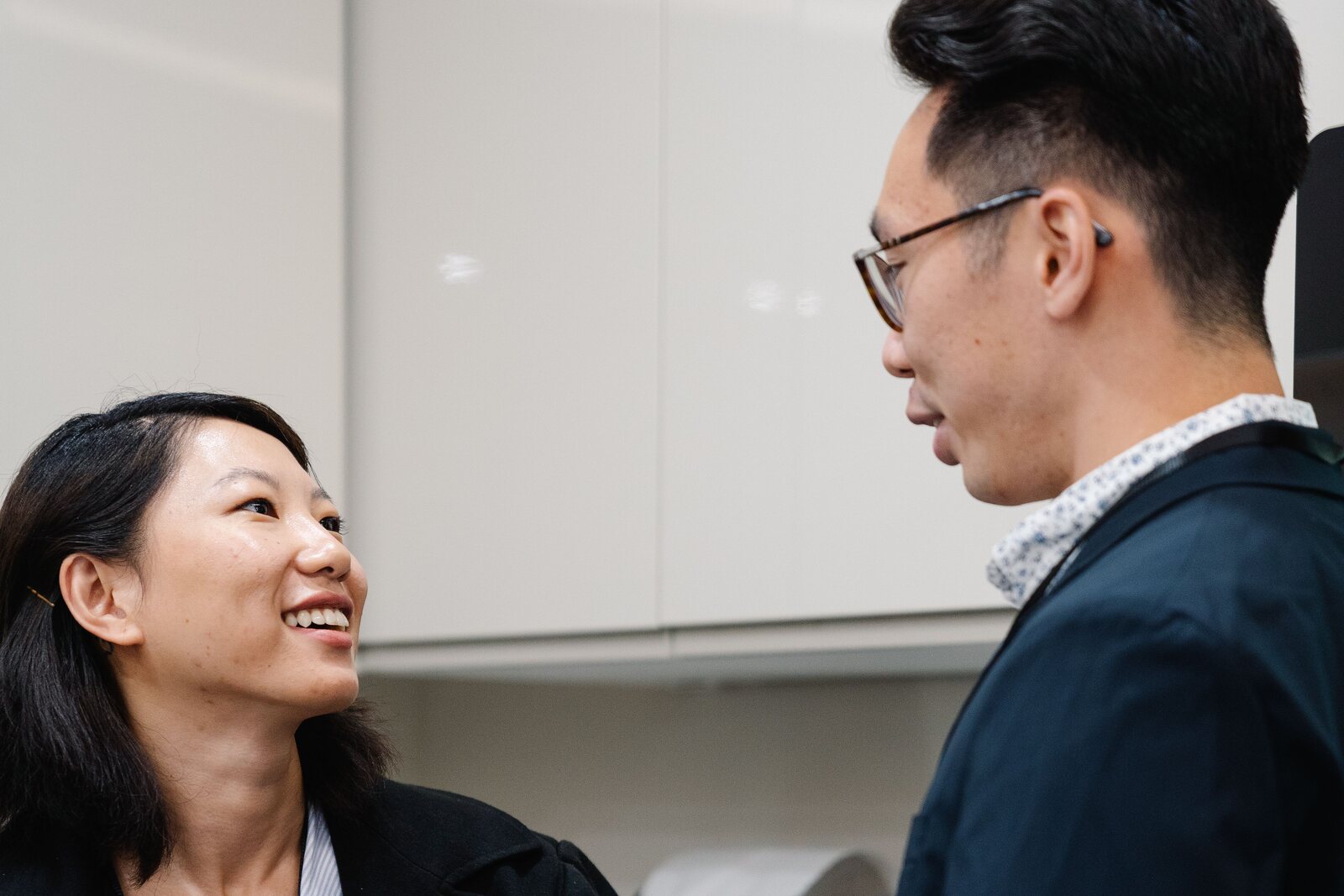 Two Asian colleagues having a friendly workplace conversation