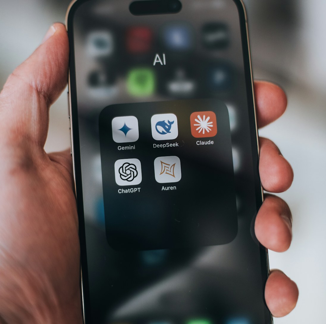 Hand holding a phone with AI application icons